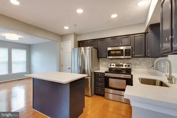a kitchen with stainless steel appliances granite countertop a sink stove microwave and refrigerator