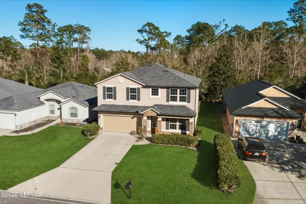 a front view of a house with a garden and trees