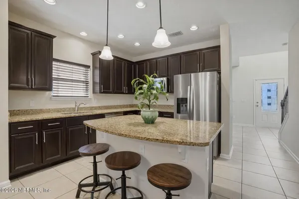 a kitchen with stainless steel appliances granite countertop a kitchen island a stove a dining table and chairs
