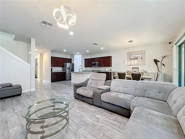 a living room with furniture kitchen view and a chandelier