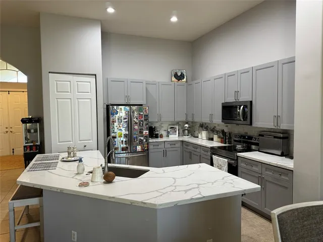 a kitchen with stainless steel appliances kitchen island sink refrigerator and microwave