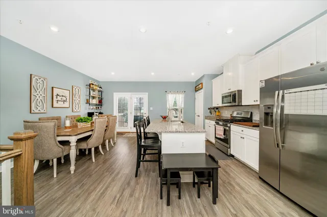 a living room with stainless steel appliances furniture dining table and wooden floor