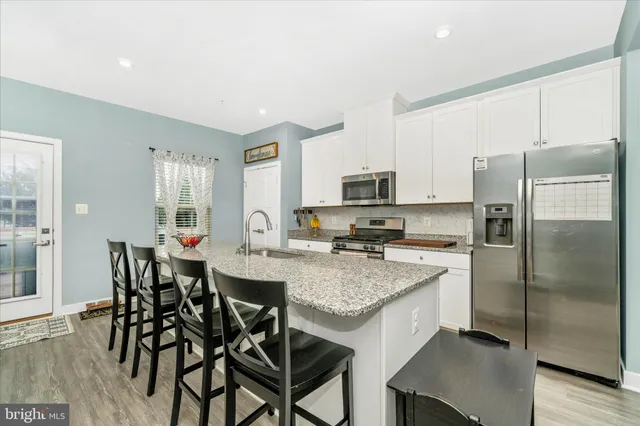 a kitchen with stainless steel appliances granite countertop a table chairs refrigerator and microwave