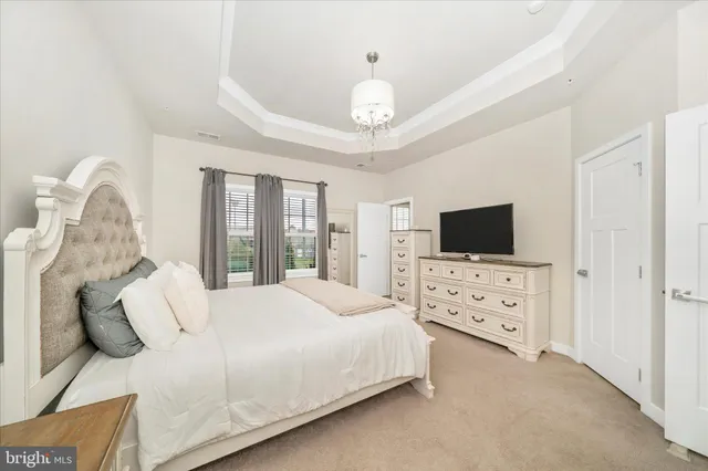 a bedroom with bed a flat tv screen and a dresser