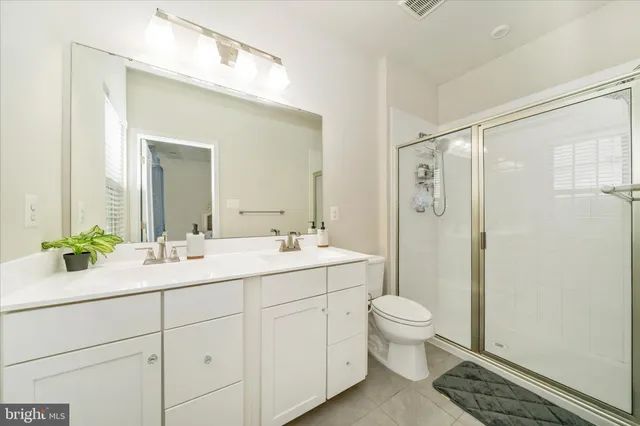 a bathroom with a double vanity sink toilet mirror and shower