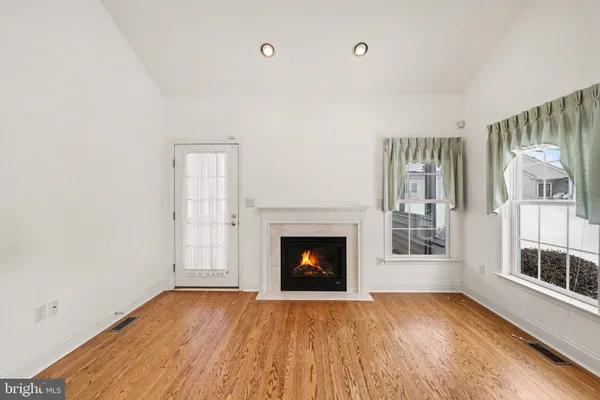 a view of an empty room with wooden floor fireplace and a window