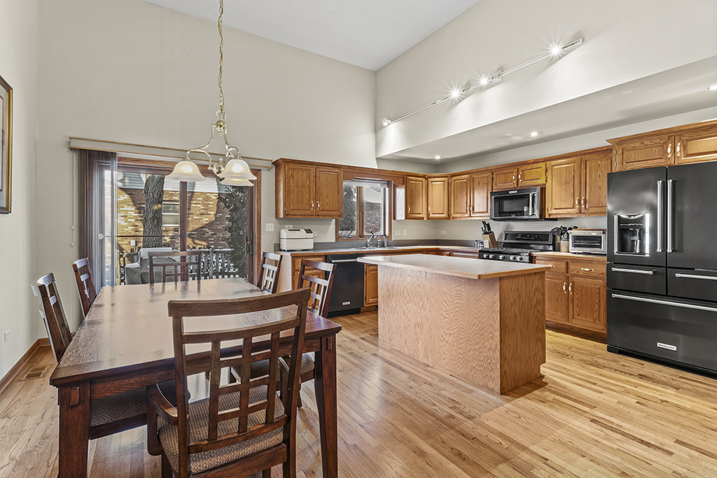 1011 Ranchwood Drive Shorewood, IL 60404 - Photo 3 of 18 a kitchen with stainless steel appliances kitchen island granite countertop a table chairs and a refrigerator