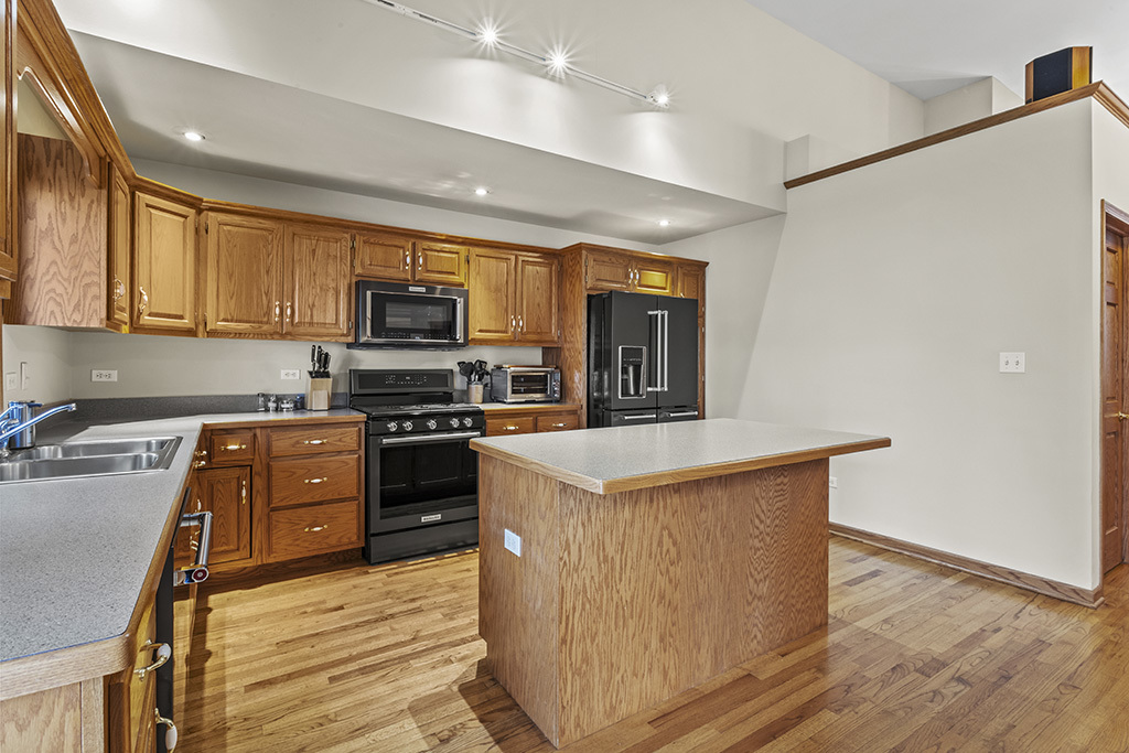 1011 Ranchwood Drive Shorewood, IL 60404 - Photo 4 of 18 a kitchen with stainless steel appliances a stove top oven a sink a refrigerator white cabinets and wooden floor