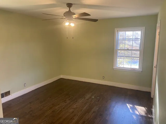 an empty room with wooden floor chandelier fan and windows