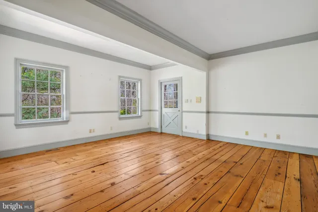 a view of an empty room with wooden floor and stairs