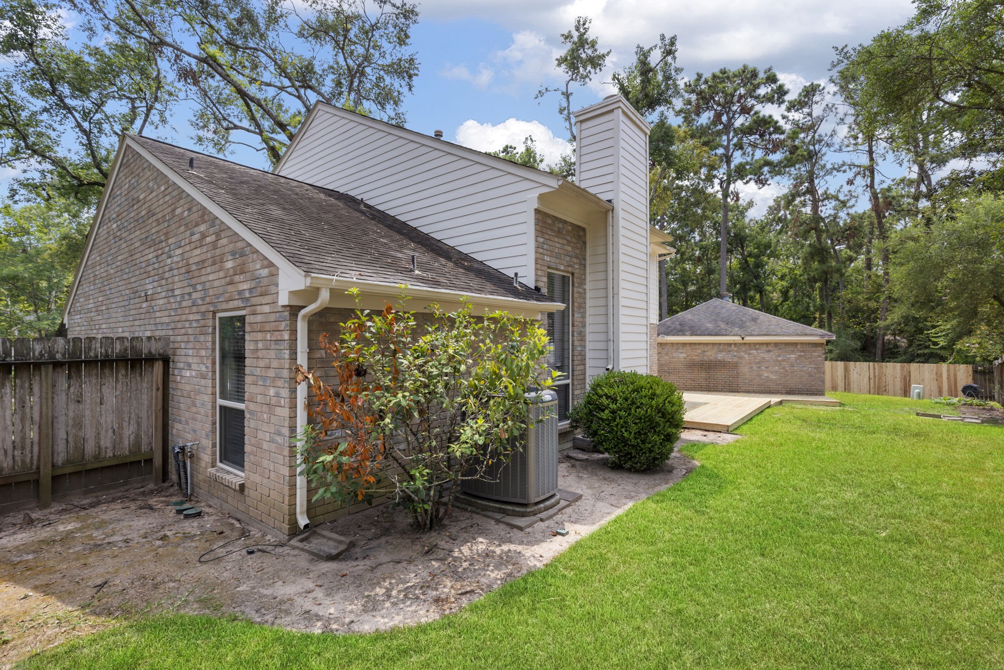 59 Fire Flicker Place Spring, TX 77381 - Photo 29 of 37 Charming brick home with a well-maintained yard, featuring a small deck and surrounded by lush greenery. The property is fenced, providing privacy and a cozy outdoor space.