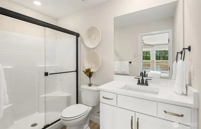 a bathroom with a sink a toilet a mirror and shower