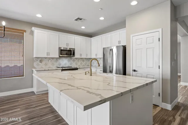 a large kitchen with stainless steel appliances granite countertop a large counter top and a wooden floors