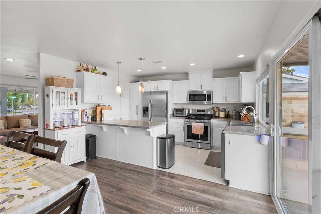 8548 Turlock Drive Riverside, CA 92504 - Photo 15 of 56 a kitchen with a refrigerator a stove top oven a sink dishwasher and white cabinets with wooden floor