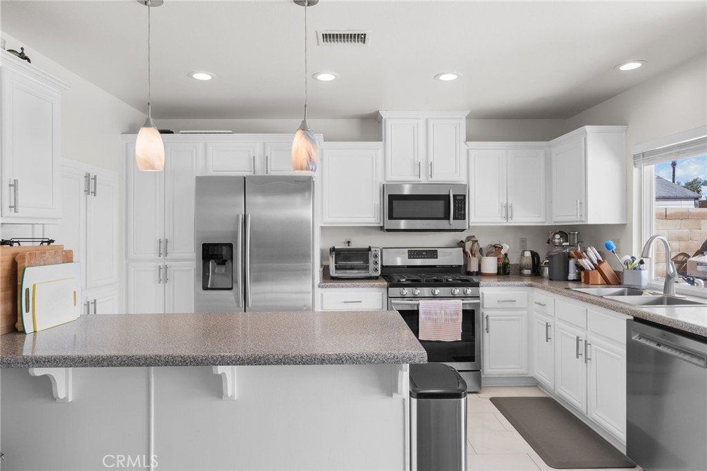 8548 Turlock Drive Riverside, CA 92504 - Photo 19 of 56 a kitchen with granite countertop a sink stainless steel appliances and white cabinets