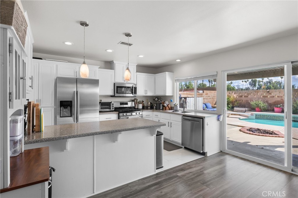 8548 Turlock Drive Riverside, CA 92504 - Photo 20 of 56 a kitchen with stainless steel appliances kitchen island granite countertop a refrigerator a sink a stove and white cabinets with wooden floor