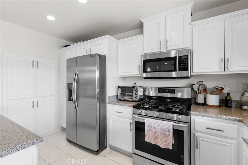 8548 Turlock Drive Riverside, CA 92504 - Photo 23 of 56 a kitchen with stainless steel appliances granite countertop a refrigerator a stove a microwave and cabinets