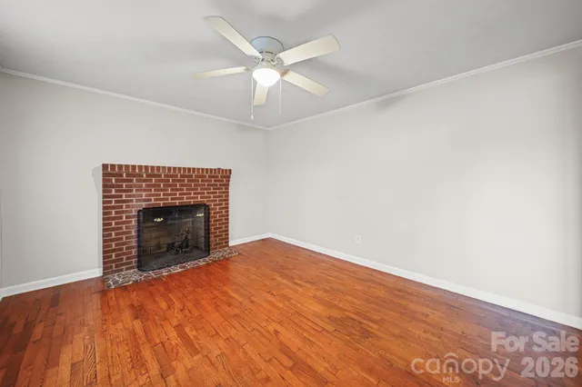 an empty room with a fireplace and ceiling fan
