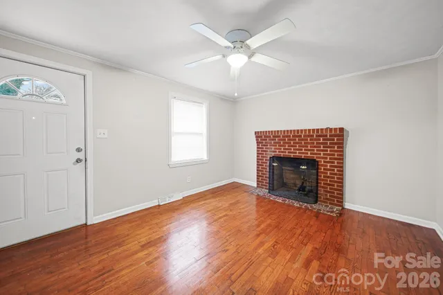 an empty room with wooden floor fireplace and window