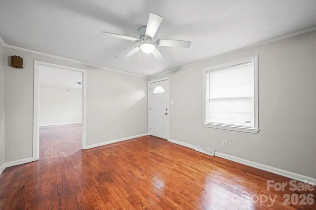 an empty room with wooden floor fan and windows