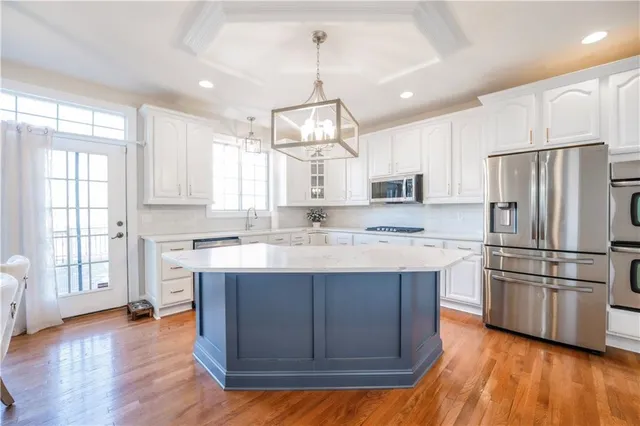 a kitchen with kitchen island granite countertop wooden floors and stainless steel appliances