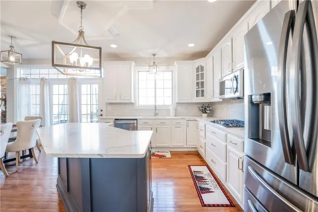 a large kitchen with stainless steel appliances granite countertop a stove a sink dishwasher and a refrigerator with wooden floor