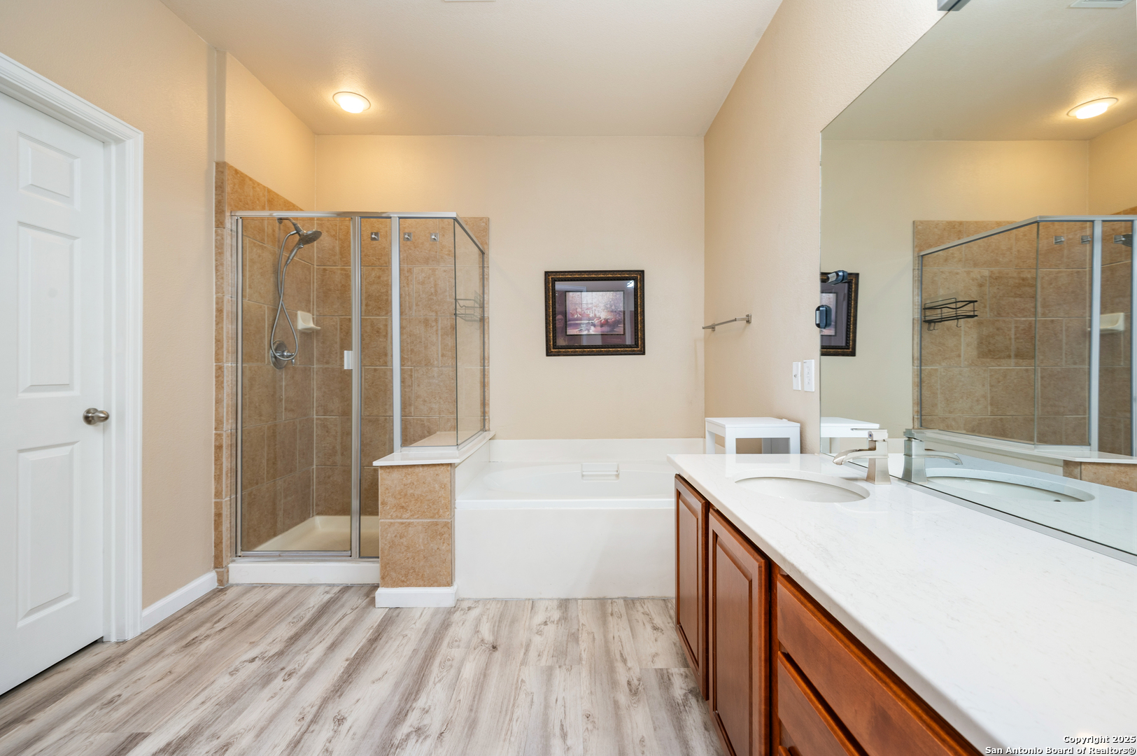 10414 Rainbow View Helotes, TX 78023 - Photo 22 of 38 a bathroom with a double vanity sink a large mirror a shower and bathtub