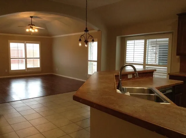 a view of a kitchen with kitchen island a sink wooden floor and a large window