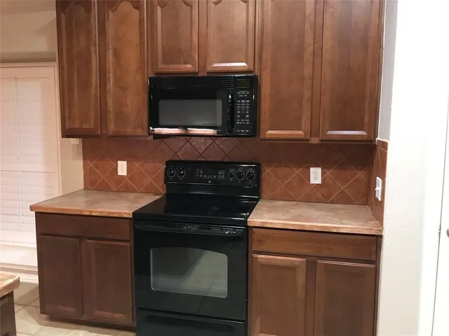 a kitchen with granite countertop wood cabinets and a stove top oven