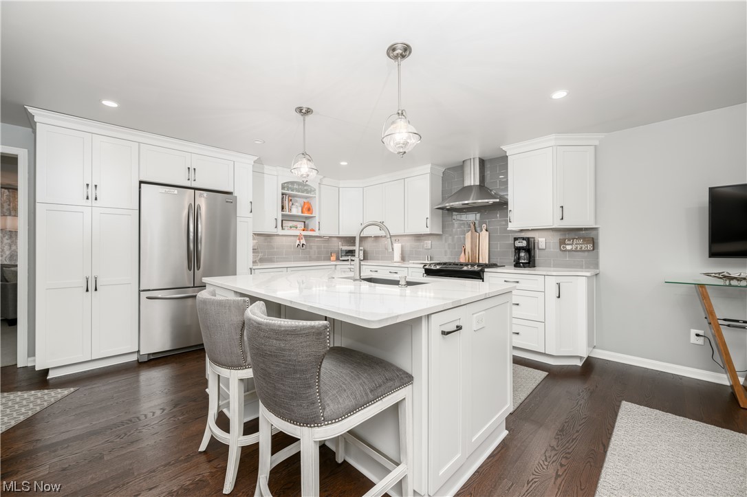 5304 Sibila Road Northwest Canton, OH 44718 - Photo 20 of 29 Kitchen featuring wall chimney range hood, a center island with sink, stainless steel fridge, and dark hardwood / wood-style flooring