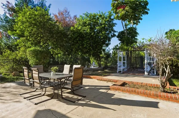 a view of a patio with table and chairs and potted plants and large trees