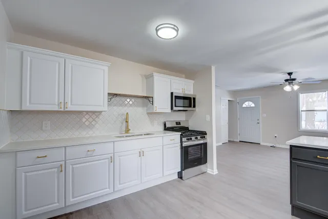a kitchen with white cabinets and appliances