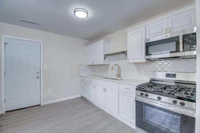 a kitchen with stainless steel appliances white cabinets and a stove top oven