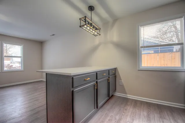 an empty room with wooden floor cabinet and windows