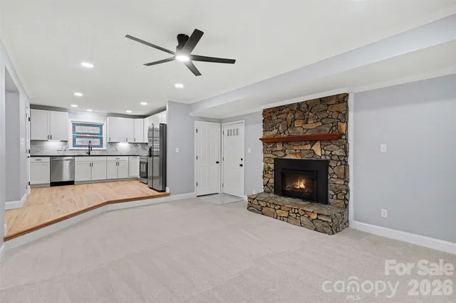 a living room with stainless steel appliances kitchen island a fireplace and a ceiling fan