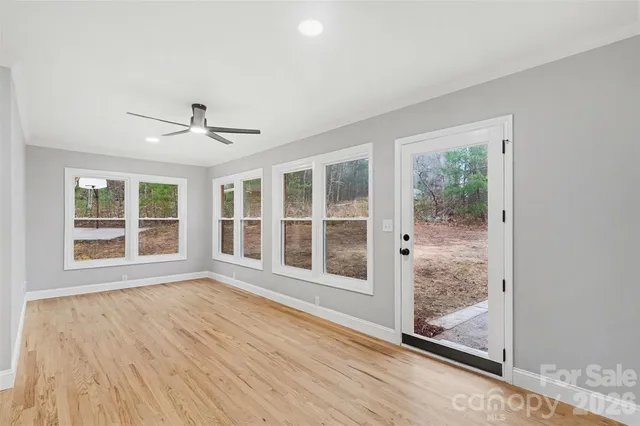 a view of an empty room with a window and wooden floor