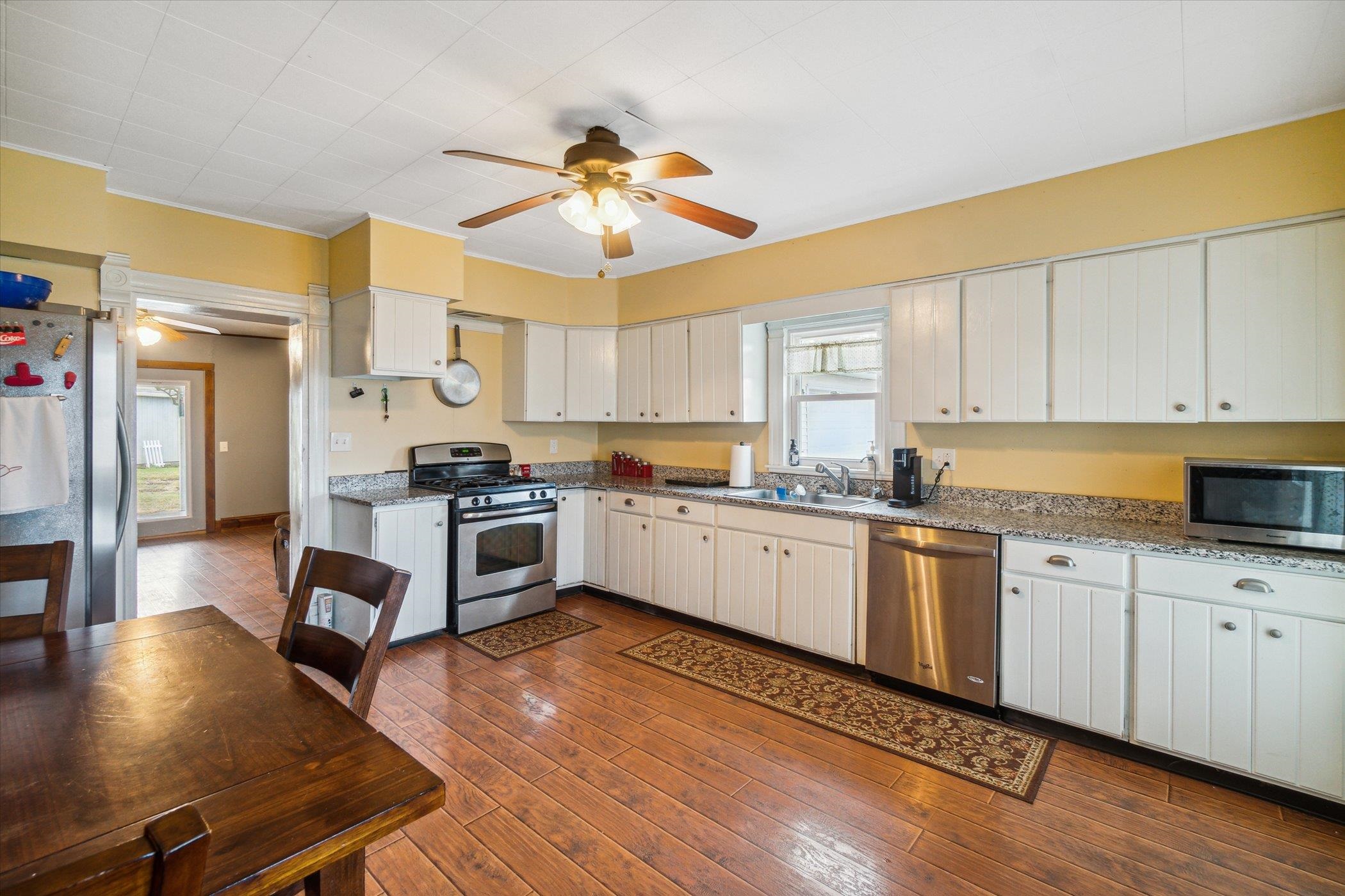 14188 Beloit Road Caledonia, IL 61011 - Photo 17 of 42 a kitchen with stainless steel appliances white cabinets a sink a stove a refrigerator and island with wooden floor