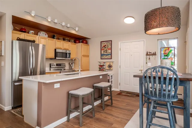 a kitchen with stainless steel appliances a table chairs refrigerator and microwave