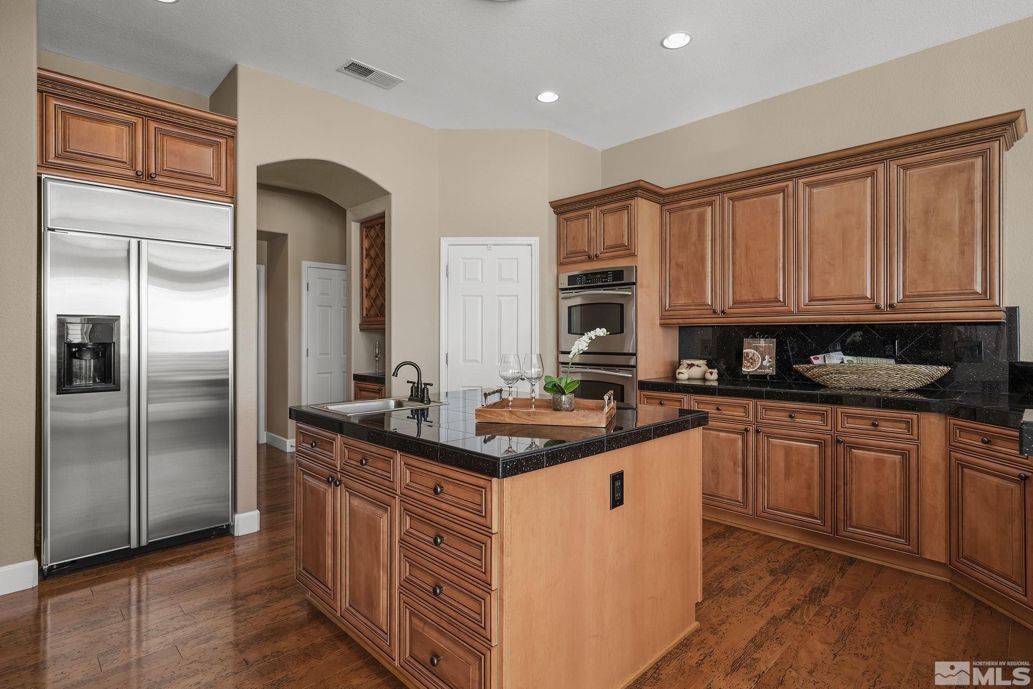 6982 Peacepipe Court Reno, NV 89511 - Photo 7 of 28 a kitchen with stainless steel appliances granite countertop a stove a sink and a refrigerator