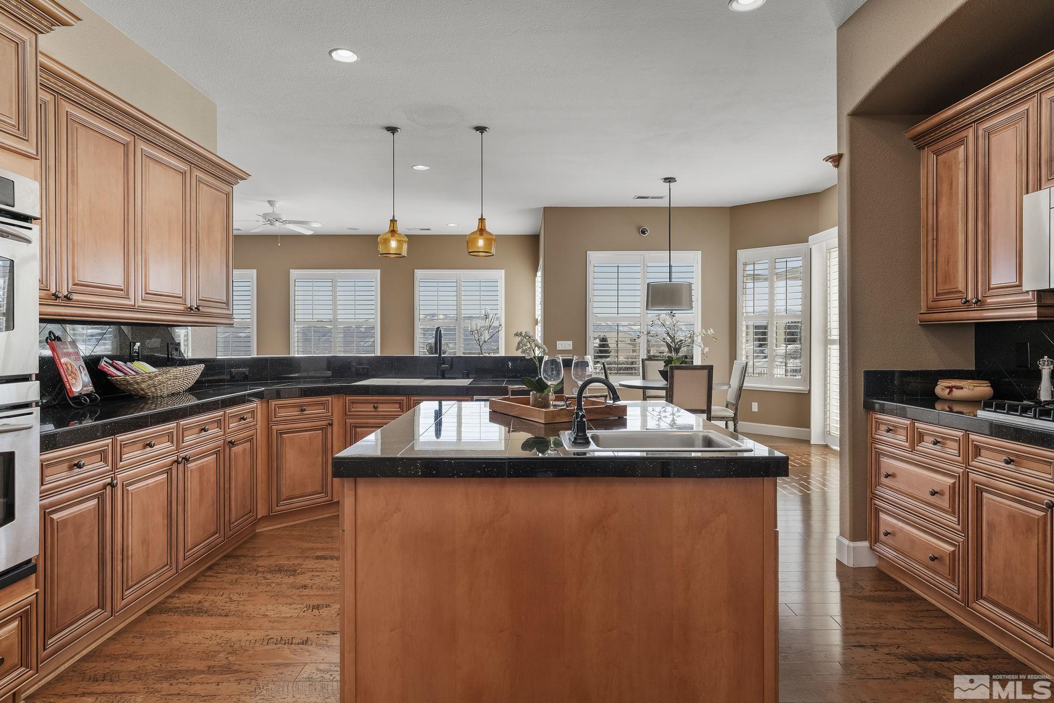 6982 Peacepipe Court Reno, NV 89511 - Photo 8 of 28 a kitchen with stainless steel appliances granite countertop a sink a stove and a wooden floors