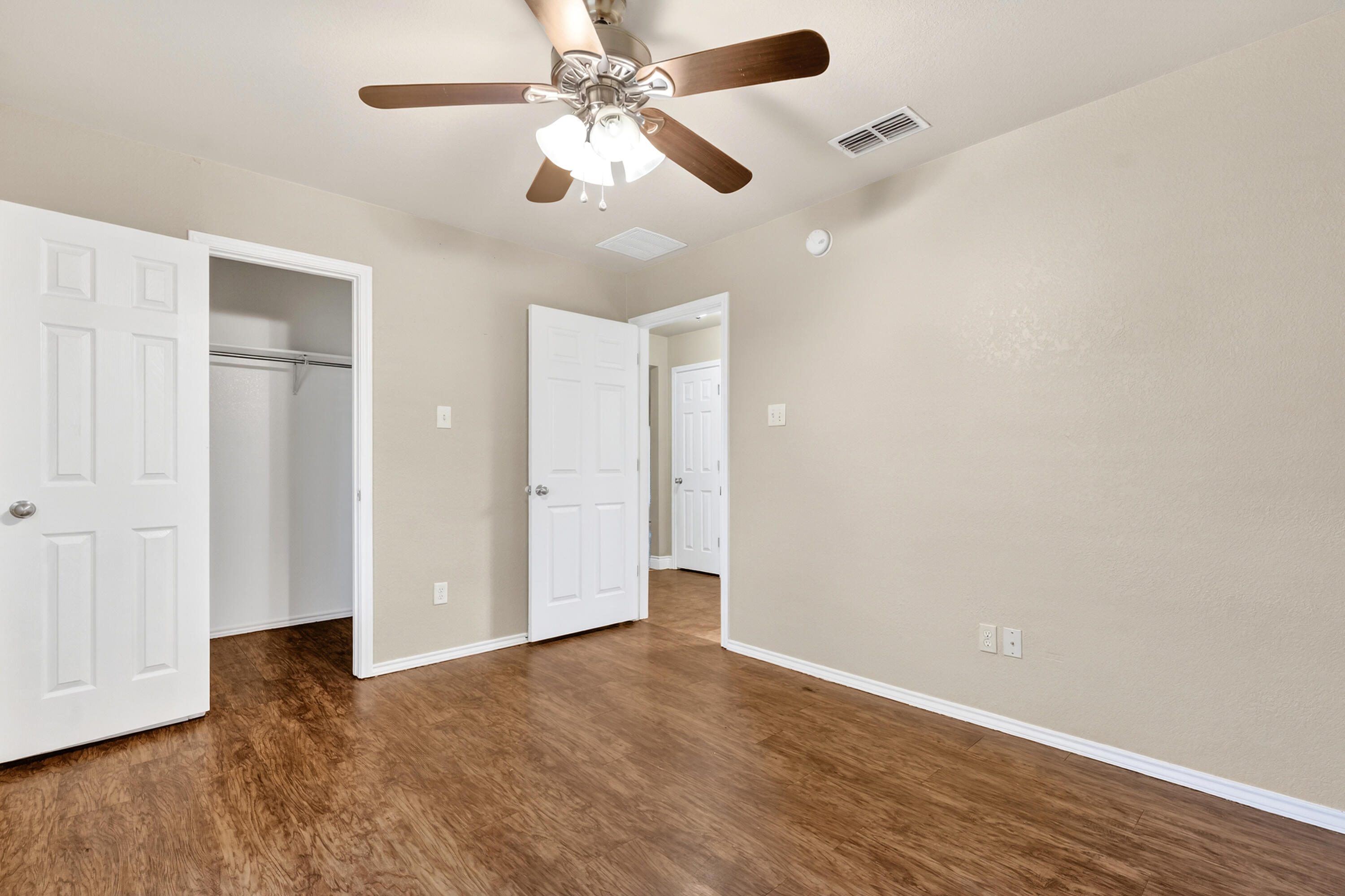 2415 93rd Street Lubbock, TX 79423 - Photo 18 of 24 an empty room with wooden floor ceiling fan and windows