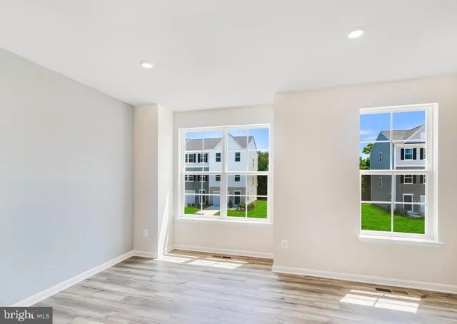 a view of an empty room with window and wooden floor