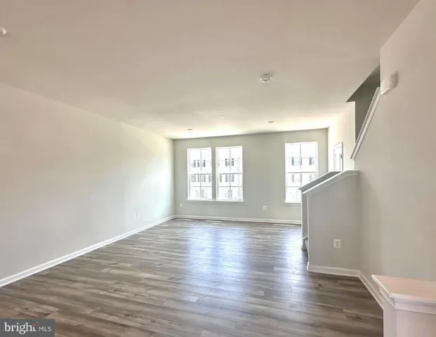 a view of an empty room with wooden floor and window