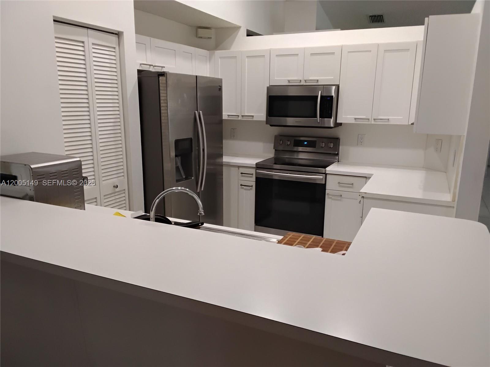 519 Talavera Road Weston, FL 33326 - Photo 9 of 19 a kitchen with stainless steel appliances a stove a microwave and a refrigerator