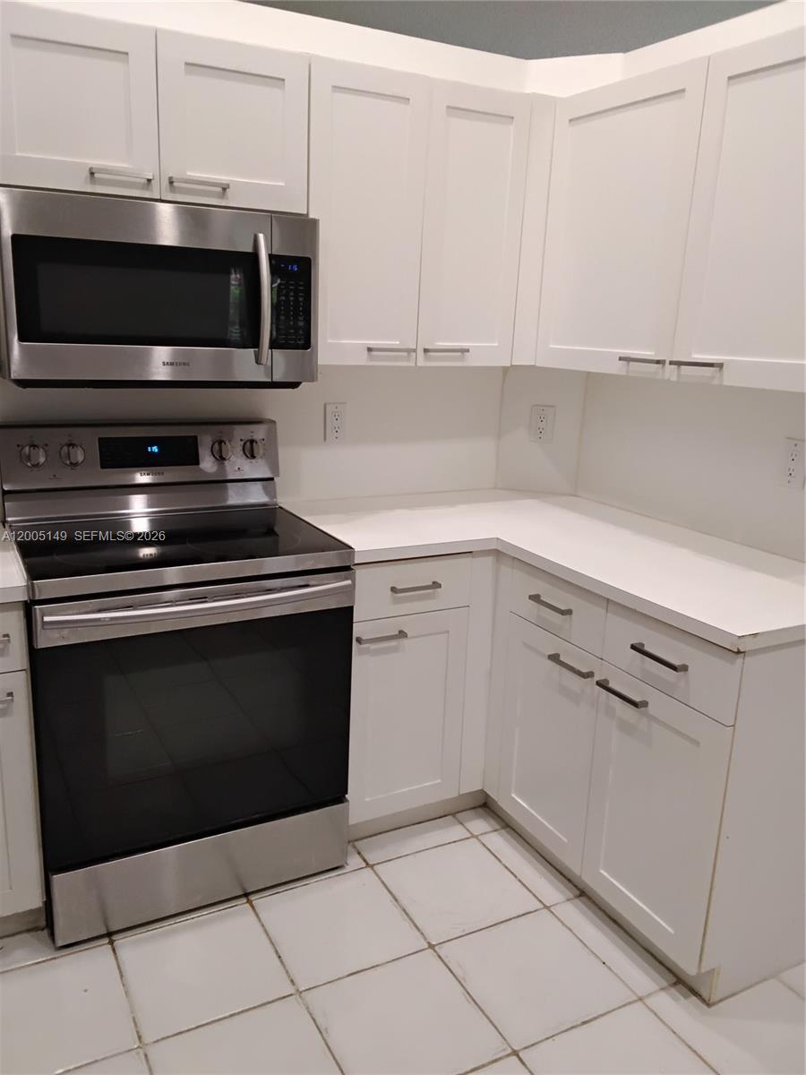 519 Talavera Road Weston, FL 33326 - Photo 10 of 19 a kitchen with white cabinets and stainless steel appliances