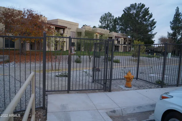 a view of a brick house with large trees and wooden fence