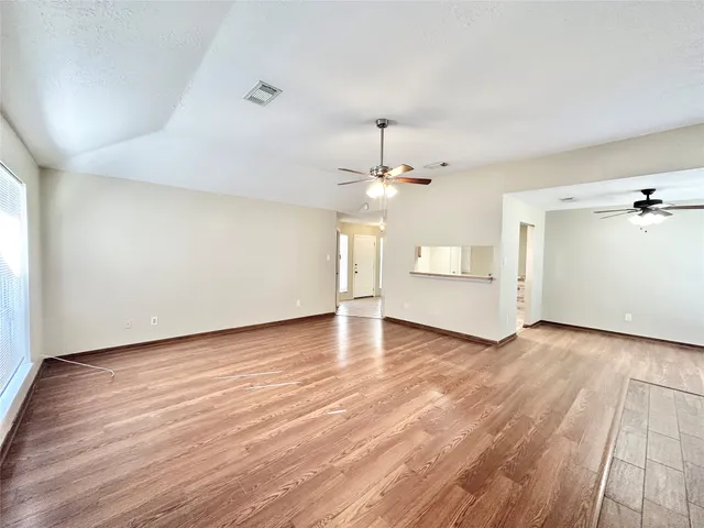 an empty room with wooden floor chandelier and windows