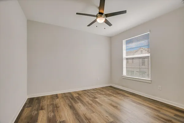 an empty room with a window and a ceiling fan