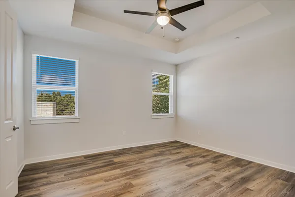a view of empty room with wooden floor and fan