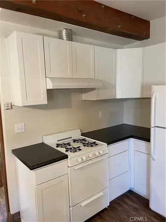 a kitchen with granite countertop white cabinets and white appliances